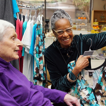 Two volunteers in gift shop showing wares